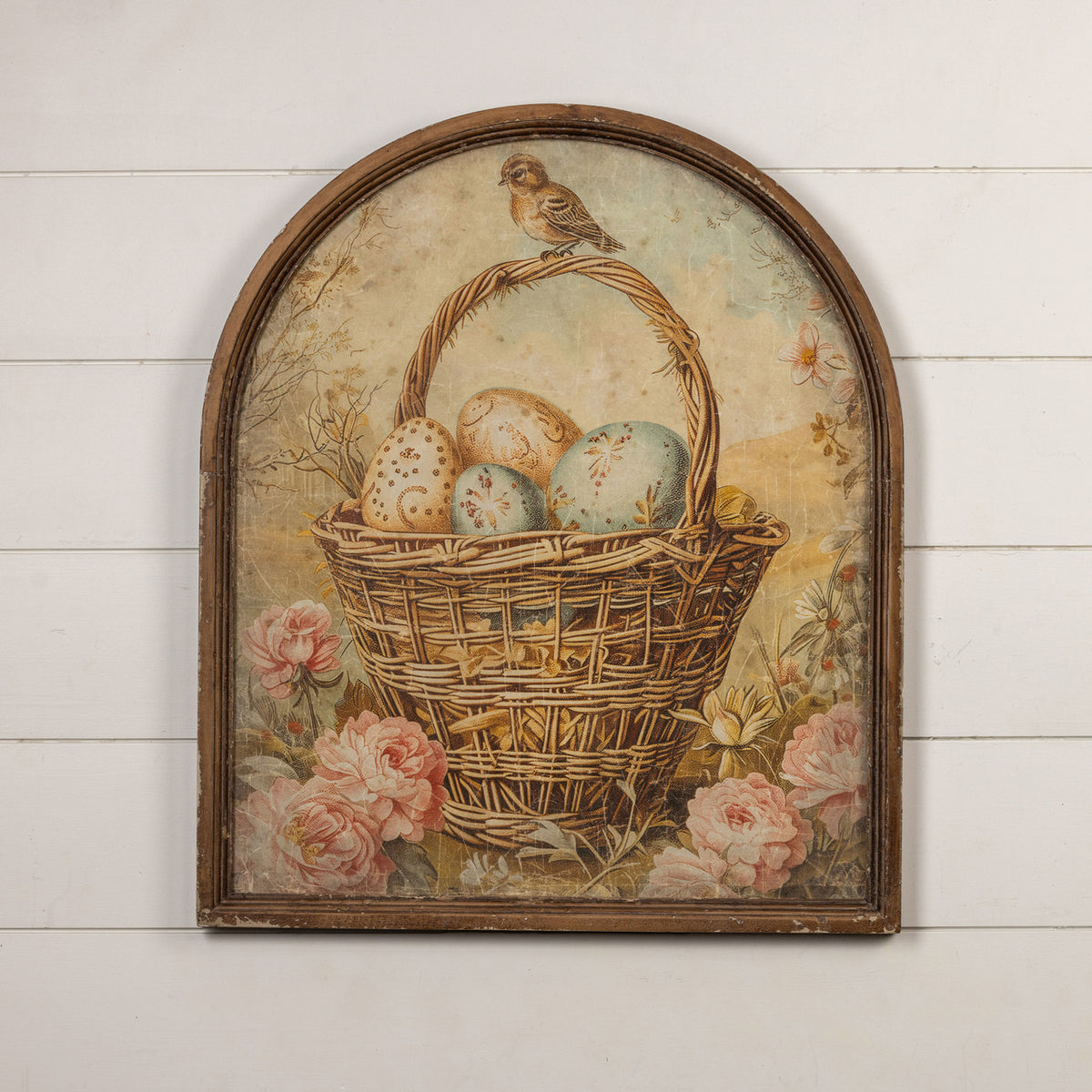 Arched framed print showing eggs in a basket with glass front and wood frame.