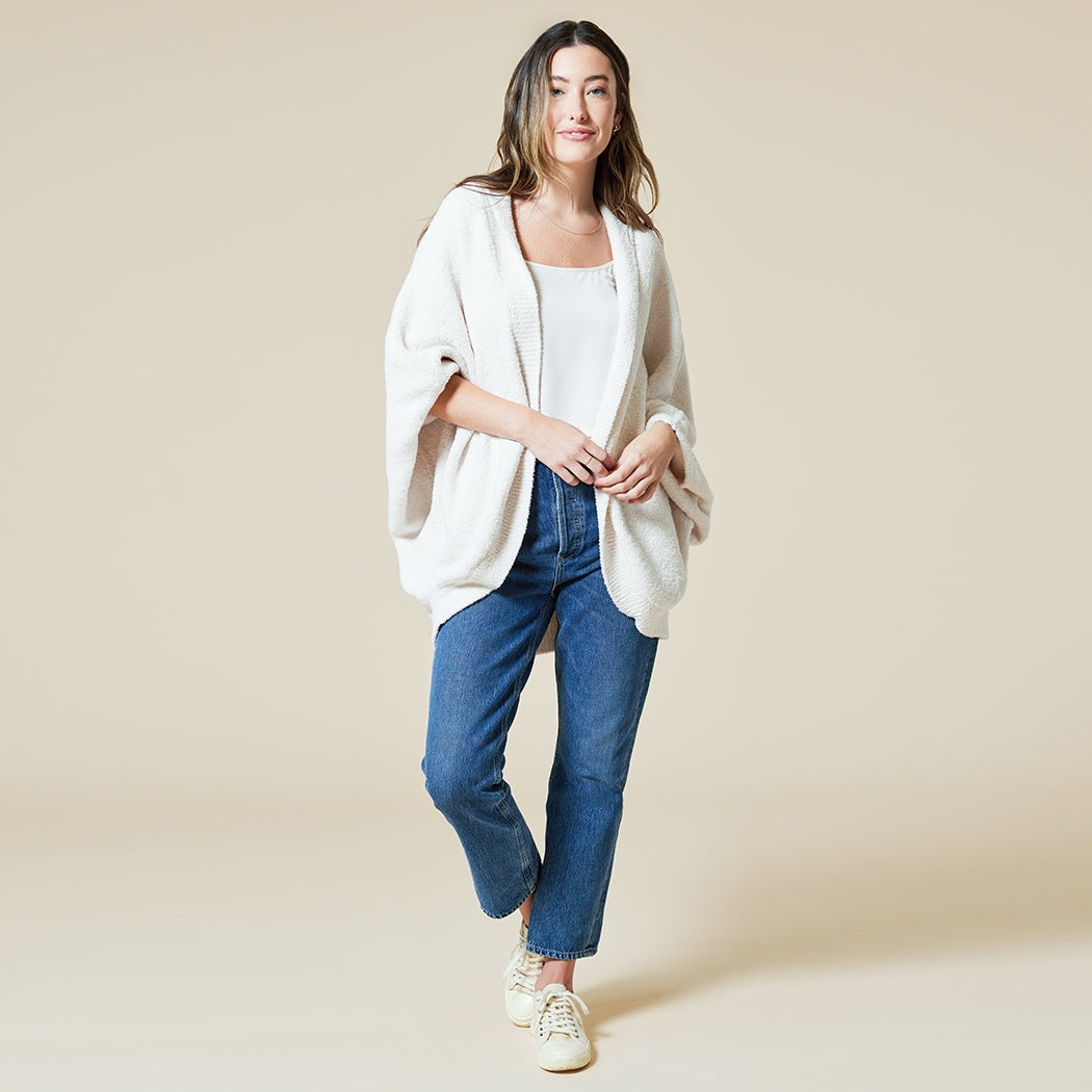 Woman wearing a Solid Marshmallow Shrug in Almond over a white top and blue jeans.