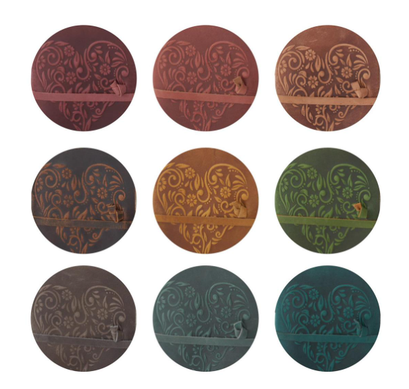 Nine 8-inch leather journals with embossed floral heart designs in various colors.
