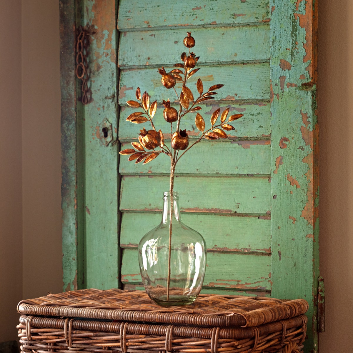 Antique gold metallic pomegranate stem sculpture with a textured fruit silhouette measuring seven inches wide.