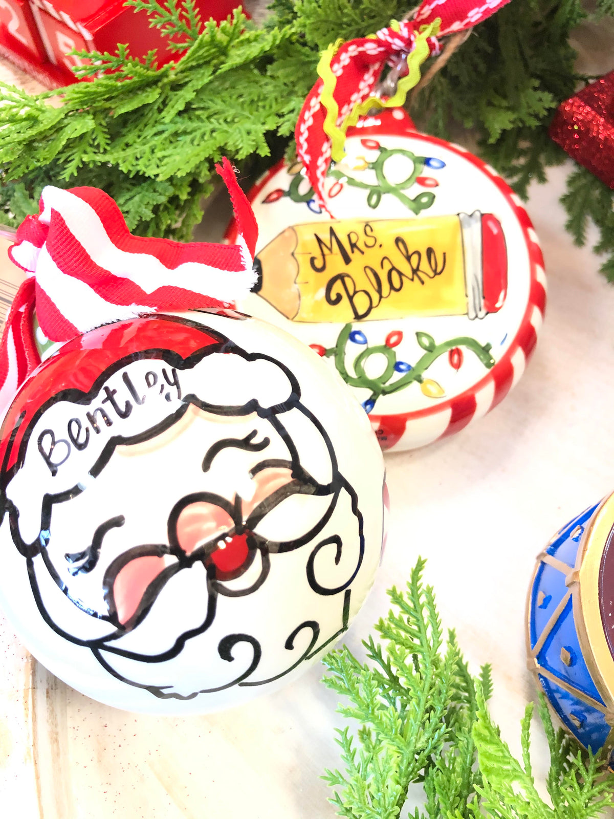 Hand-painted Christmas ornaments: Santa with name "Bentley" and pencil with "Mrs. Blake".